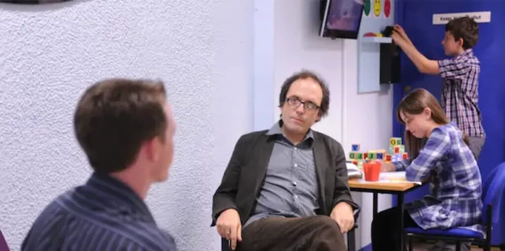 parent discussing child learning support with specialist in classroom setting